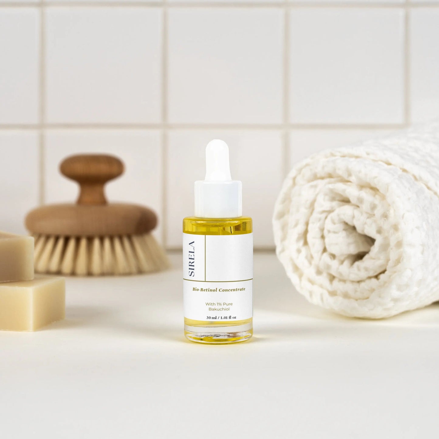 SIRELA skincare dropper bottle on a bathroom counter with a brush and towel in the background.